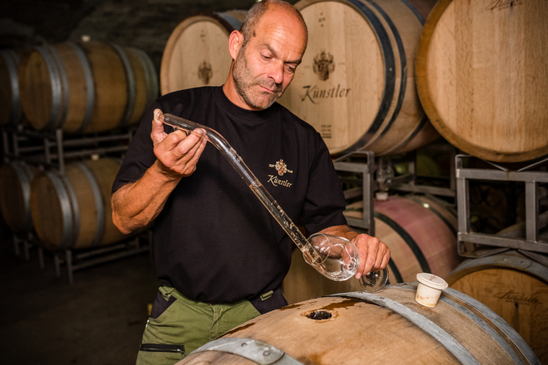 Kellermeister Rolf Schregel entnimmt eine Weinprobe aus dem Barrique